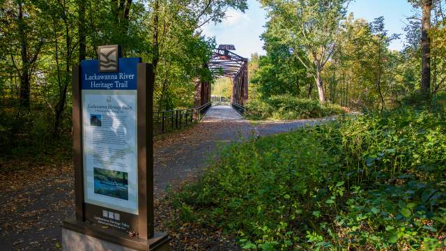 Sign and railroad bridge along the Lackawanna River Heritage Trail