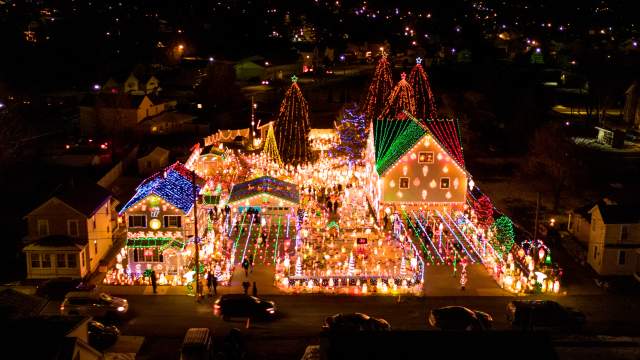 Aerial nighttime view of Peckville, PA neighborhood with colorful Christmas lights, decorated houses, and illuminated trees during the holiday season.