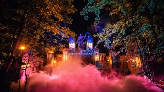 Colorful lights and dense fog surround a haunted castle set in the woods at Reaper’s Revenge near Scranton, PA