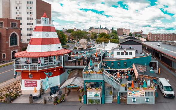 Cooper's Seafood House restaurant with a lighthouse and pirate ship design, featuring outdoor seating, decorations, and a large octopus sculpture on the top deck.