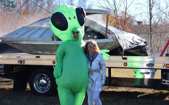 A couple dressed in alien costumes standing in front of a spaceship at The Carbondalien Festival in Carbondale, PA