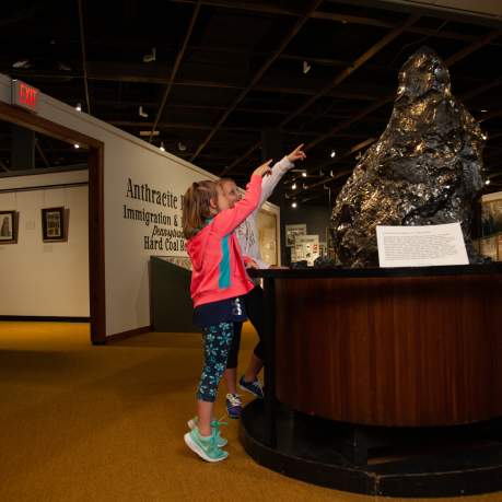 Two children pointing at a large piece of anthracite on display at the Anthracite Heritage Museum in Scranton, PA