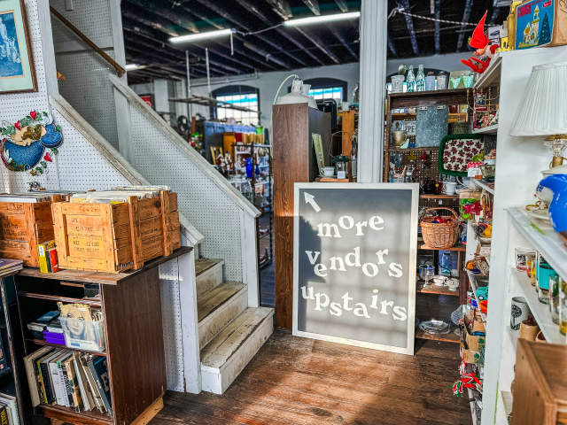 Interior shot featuring a sign that says "More Vendors Upstairs" pointing to a staircase