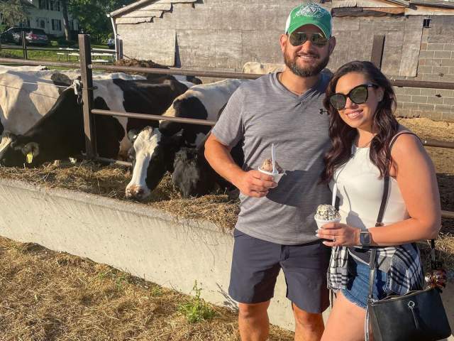 A couple posing for a pic in front of cows while holding their ice cream at Manning Farm Dairy in Dalton, PA