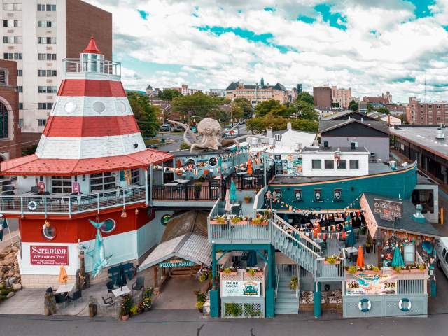 Cooper's Seafood House restaurant with a lighthouse and pirate ship design, featuring outdoor seating, decorations, and a large octopus sculpture on the top deck.