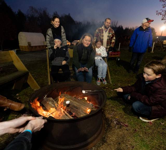 People roasting marshmallows around a campfire at Roba Family Farms