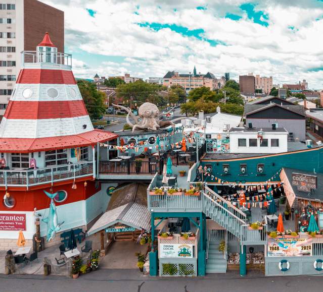 Cooper's Seafood House restaurant with a lighthouse and pirate ship design, featuring outdoor seating, decorations, and a large octopus sculpture on the top deck.