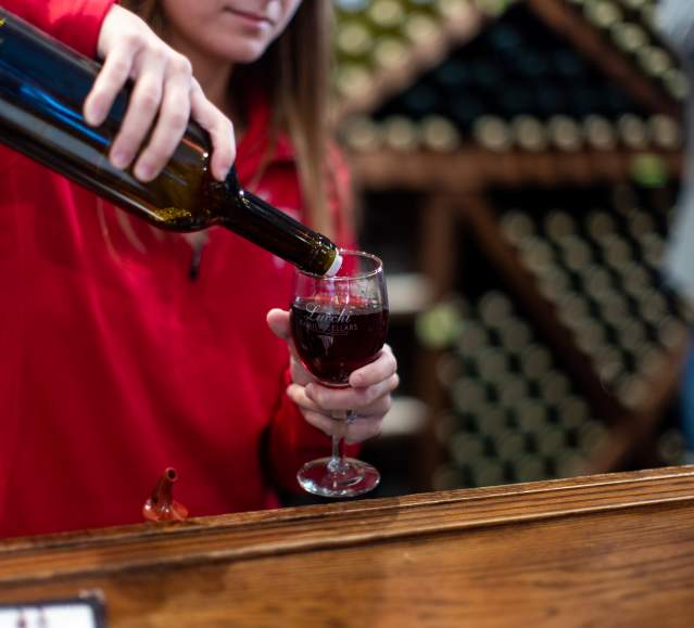 A woman pouring a glass of wine at Lucchi Family Wine Cellars in Scranton, PA