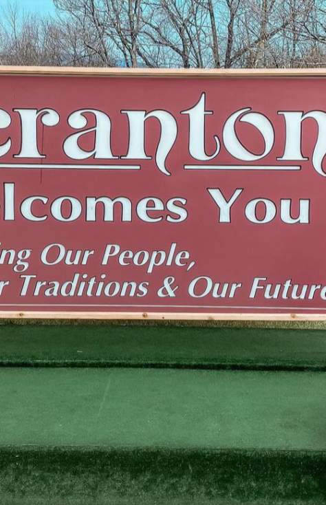 woman sitting in front of Scranton Welcomes You Sign in Downtown Scranton, PA