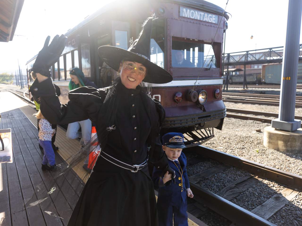 A costumed witch waves beside a child dressed as a conductor in front of a vintage trolley at the Electric City Trolley Museum in Scranton, PA.