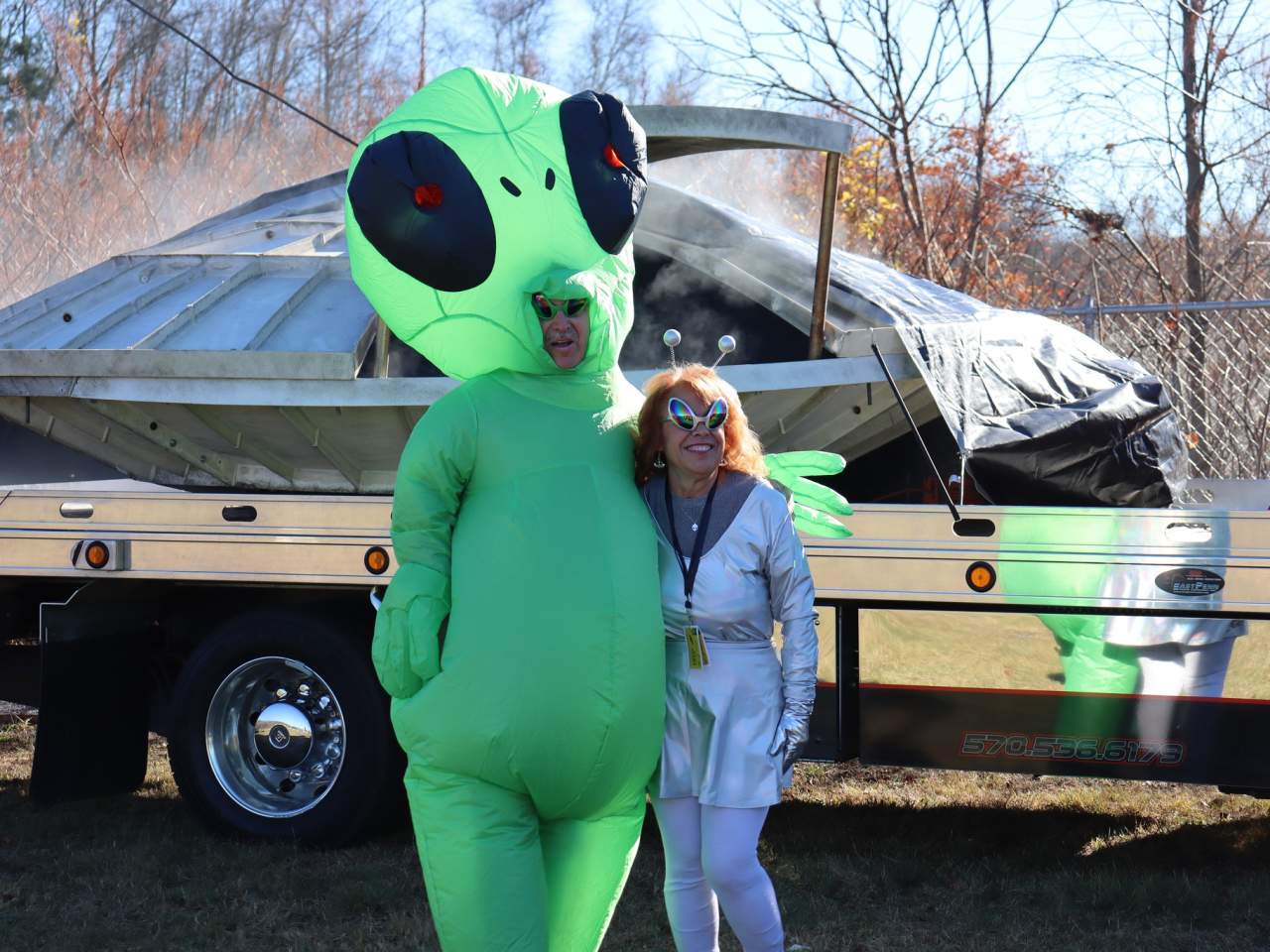 A couple dressed in alien costumes standing in front of a spaceship at The Carbondalien Festival in Carbondale, PA