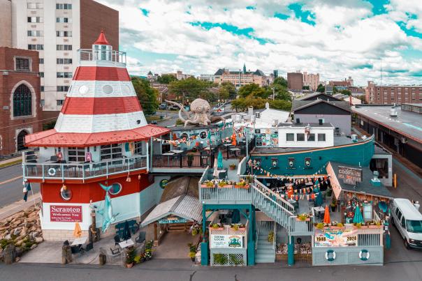 Cooper's Seafood House restaurant with a lighthouse and pirate ship design, featuring outdoor seating, decorations, and a large octopus sculpture on the top deck.