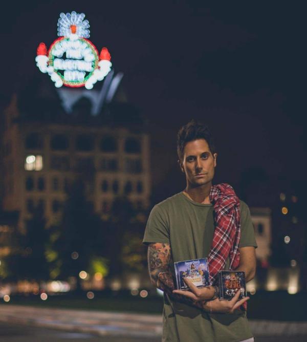 Justin Roach holding Snoop Dogg album covers that he designed