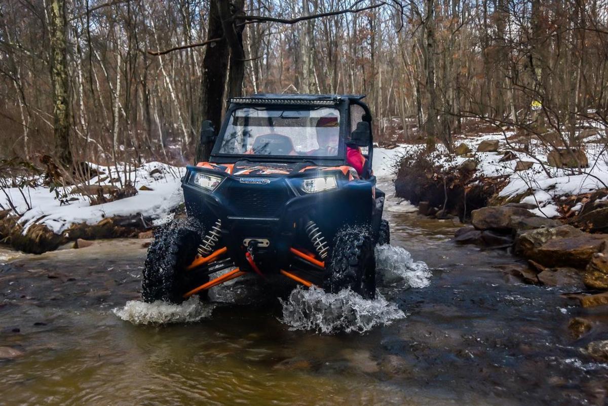 an atv driving through a creek in the wintertime