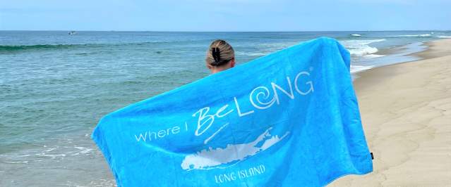 Girl at the beach with towel walking in the sand