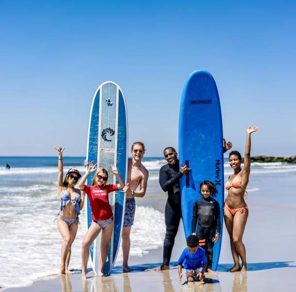 family with kids surfing at the beach