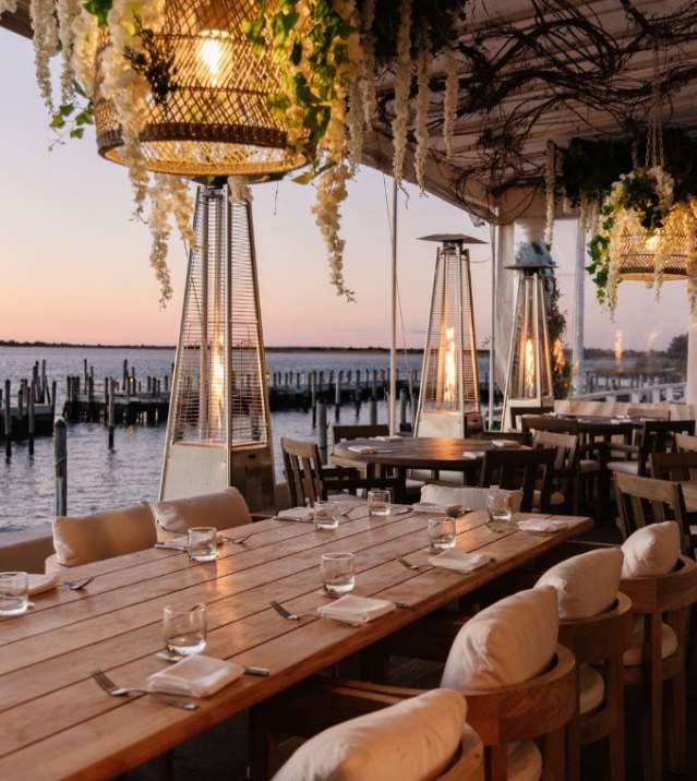 open restaurant seating area with waterfront view during sunset