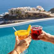 A celebratory cocktail toast over a luxury infinity pool overlooking the ocean at Casa Stella in Cabo.