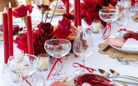 Elegant bachelorette dinner table setting with red roses, red taper candles, and white linens in Los Cabos.