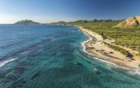 A coastline stretches out into the distance, showcasing pristine sandy beaches, clear blue waters, and rolling hills under a bright sky Cabo Pulmo