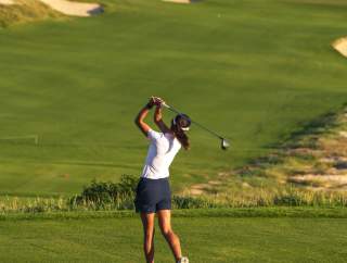 A female golfer making a swing with an ocean view