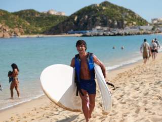 hombre saliendo del mar con tablas de surf