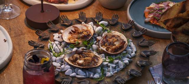 A table adorned with seafood dishes, including clams on a decorative platter, surrounded by drinks and other plates