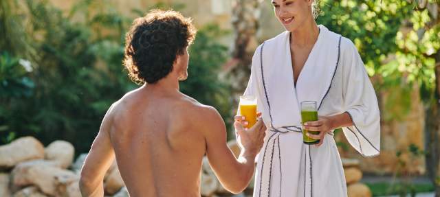 Man and women sharing smoothies by a pool