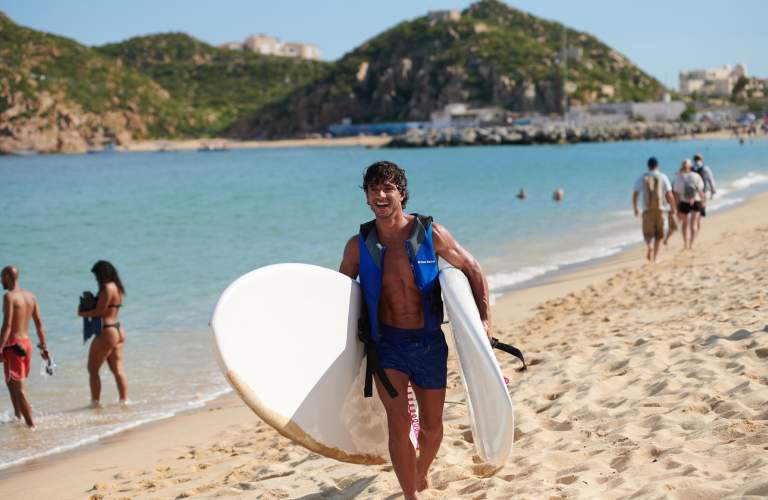 hombre saliendo del mar con tablas de surf