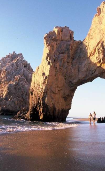 pareja caminando debajo de El Arco de Cabo San Lucas