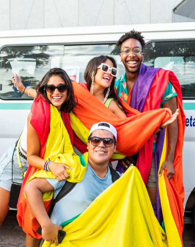 fotografía de asistentes a la marcha lgbt en los cabos cargando una bandera arcoíris