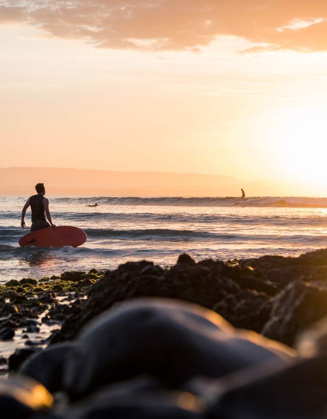 hombre mirando hacia el atardecer en una playa de los cabos
