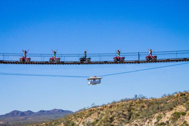 cuatro todoterreno pasando sobre un puente de madera colgante