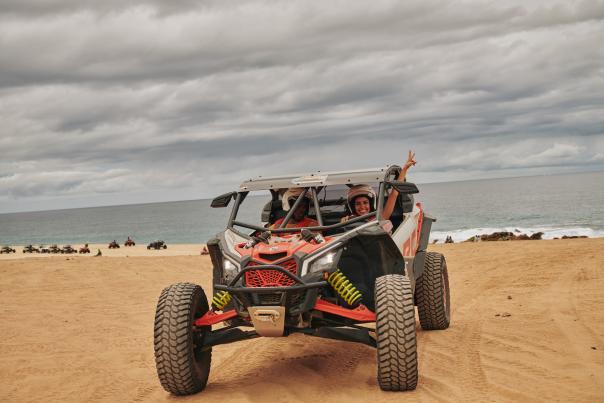 fotografía de dos personas en un automóvil ATV en el desierto