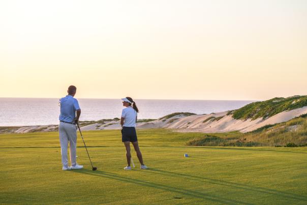 Couple male and female playing golf and admiring a beautiful sunset in Los Cabos, Mexico