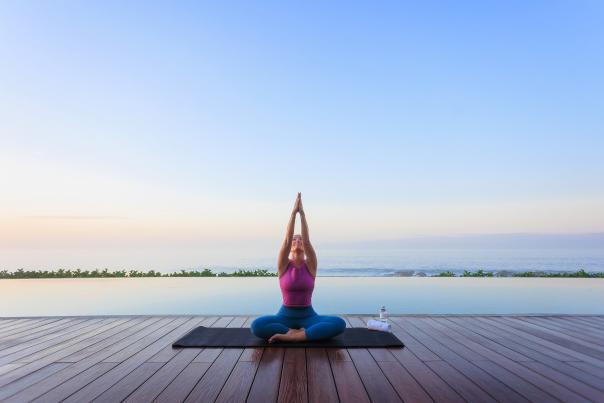 Woman doing yoga on a pier by water