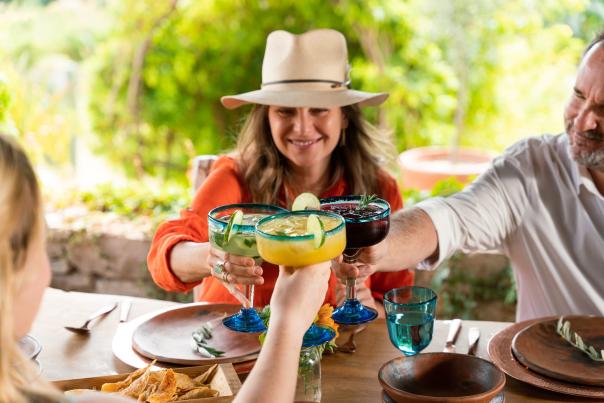 fotografía de una mujer chocando copas con su familia durante una comida en la playa