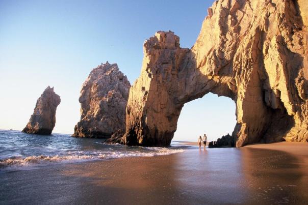 pareja caminando debajo de El Arco de Cabo San Lucas