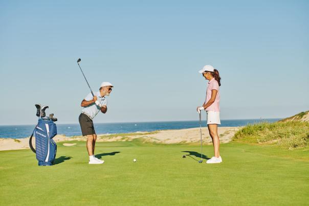fotografía de dos personas jugando golf en los cabos con vista hacia el mar
