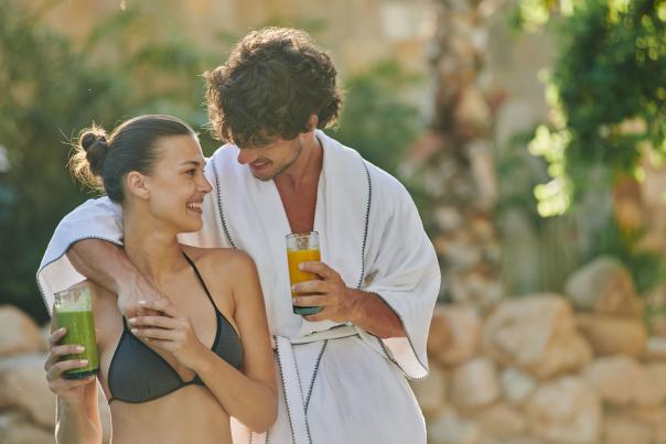 pareja heterosexual en traje de baño fuera de la alberca con jugo en la mano