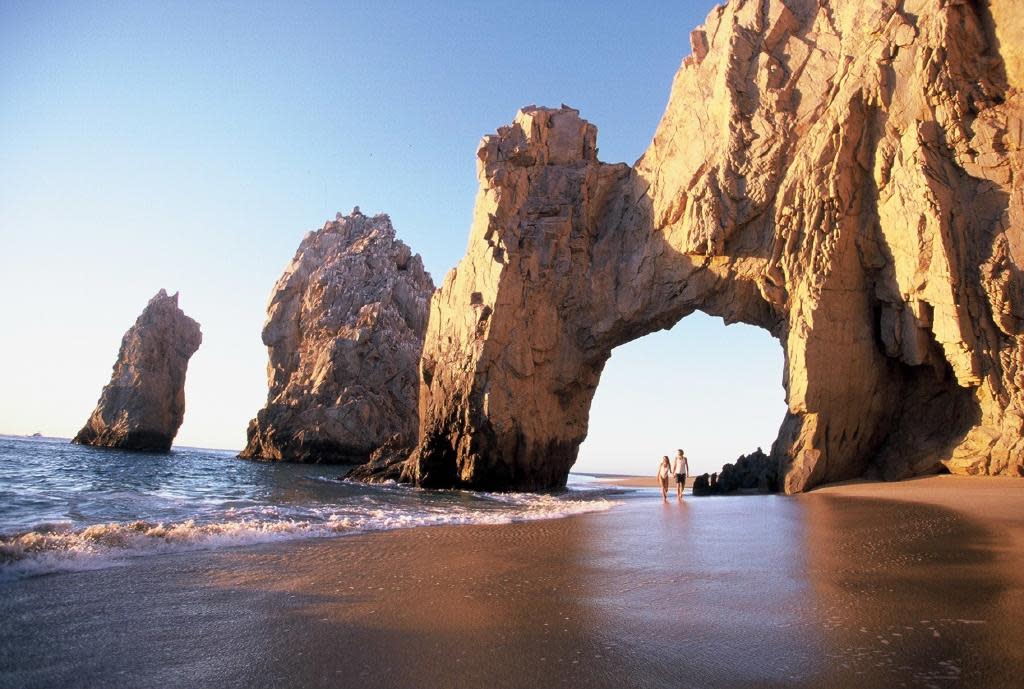 pareja caminando debajo de El Arco de Cabo San Lucas
