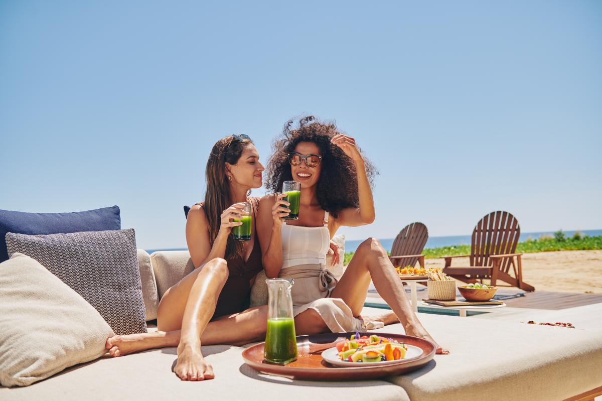 Pareja de mujeres en los cabos tomando el desayuno en la playa