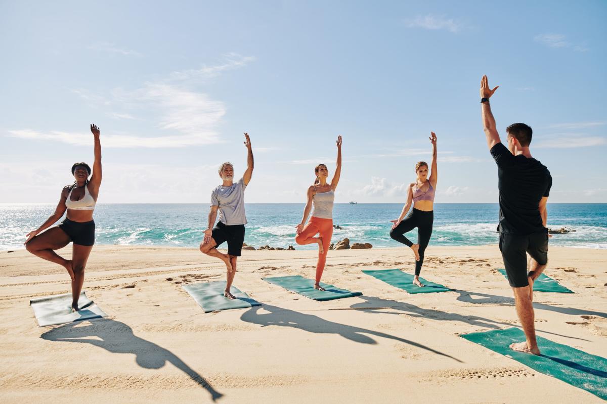 grupo de personas haciendo yoga en la playa