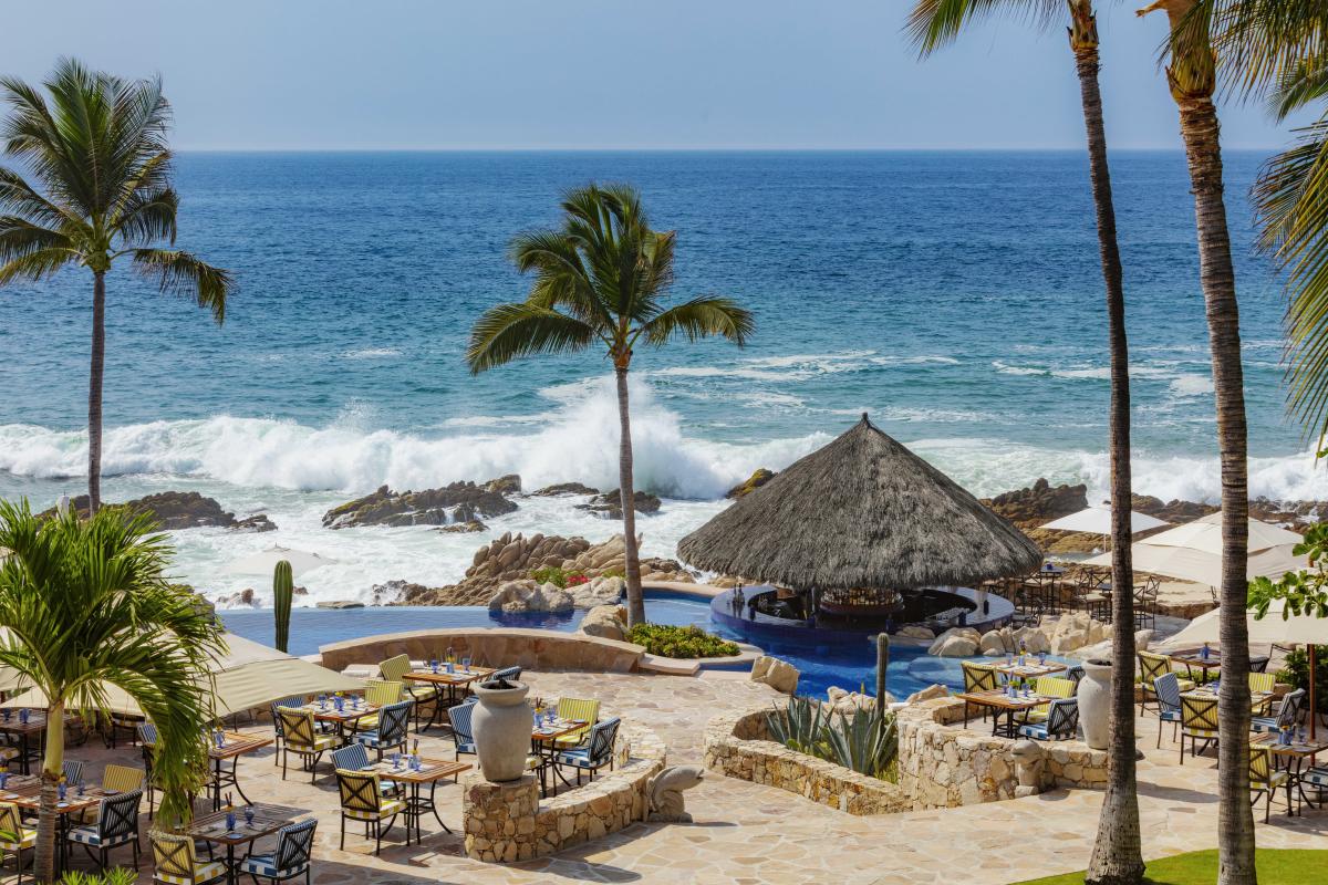 Tiered stone patio and outdoor dining tables outside of Breeze Restaurant at the One&Only Palmilla resort overlook crashing waves in San José del Cabo, Mexico.