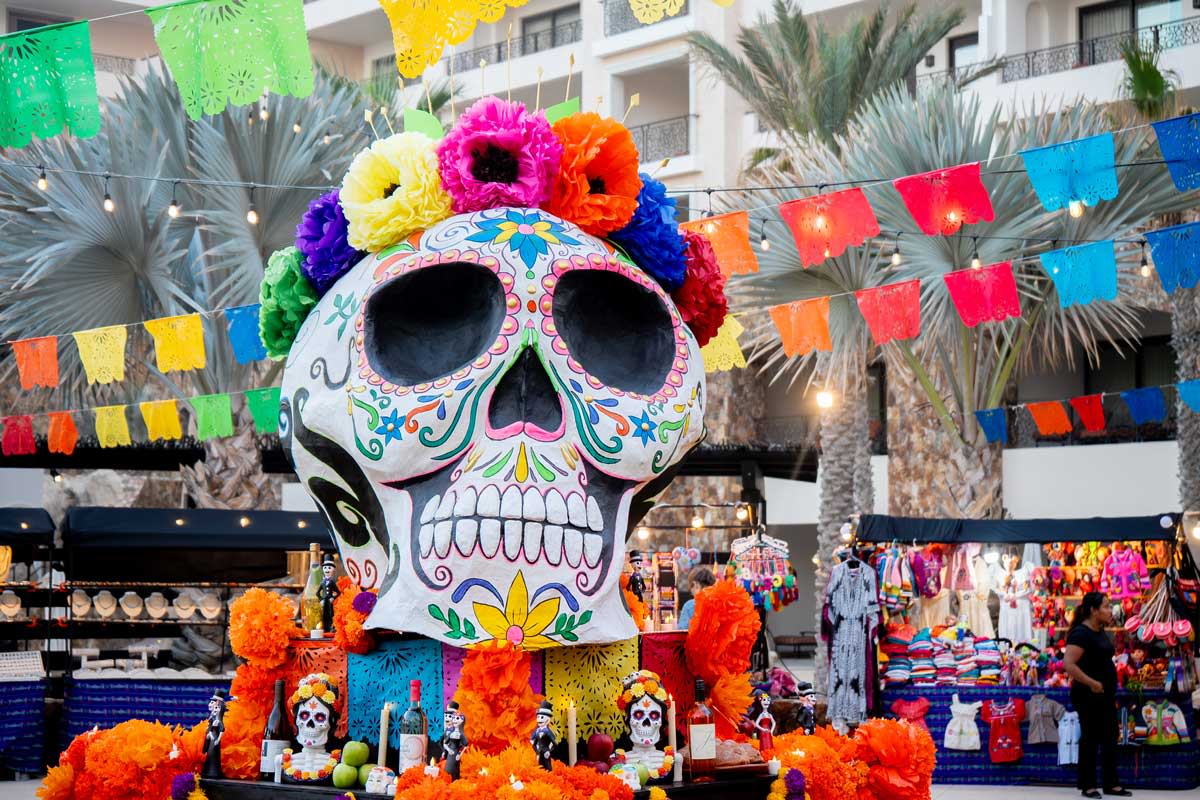 A large, brightly decorated sugar skull sculpture sits on a festive altar for Día de los Muertos in Los Cabos, Mexico