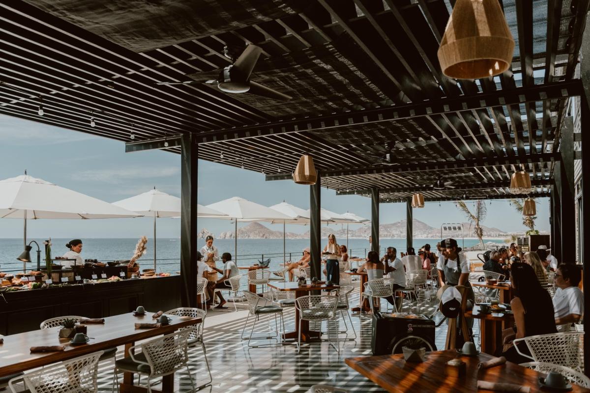 Open air restaurant at The Cape hotel with a view of the ocean and rock formations in the distance.