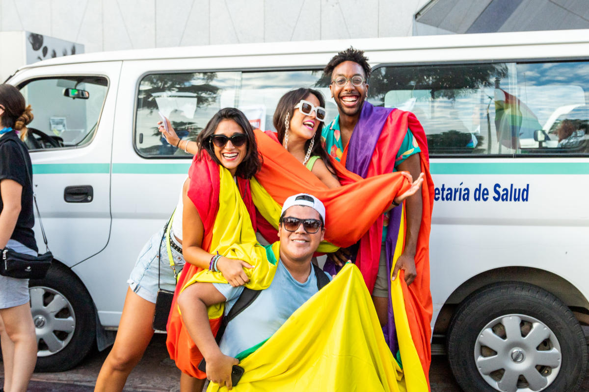 fotografía de asistentes a la marcha lgbt en los cabos cargando una bandera arcoíris