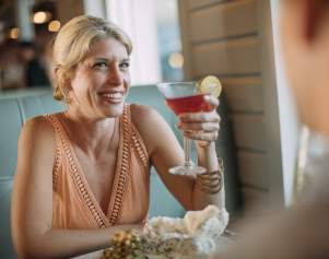 Women holding up a cocktail while sitting in a booth at a Mexican restaurant.