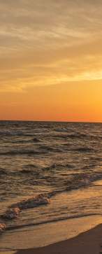 A couple walk on the beach during sunset on Valentine's Day