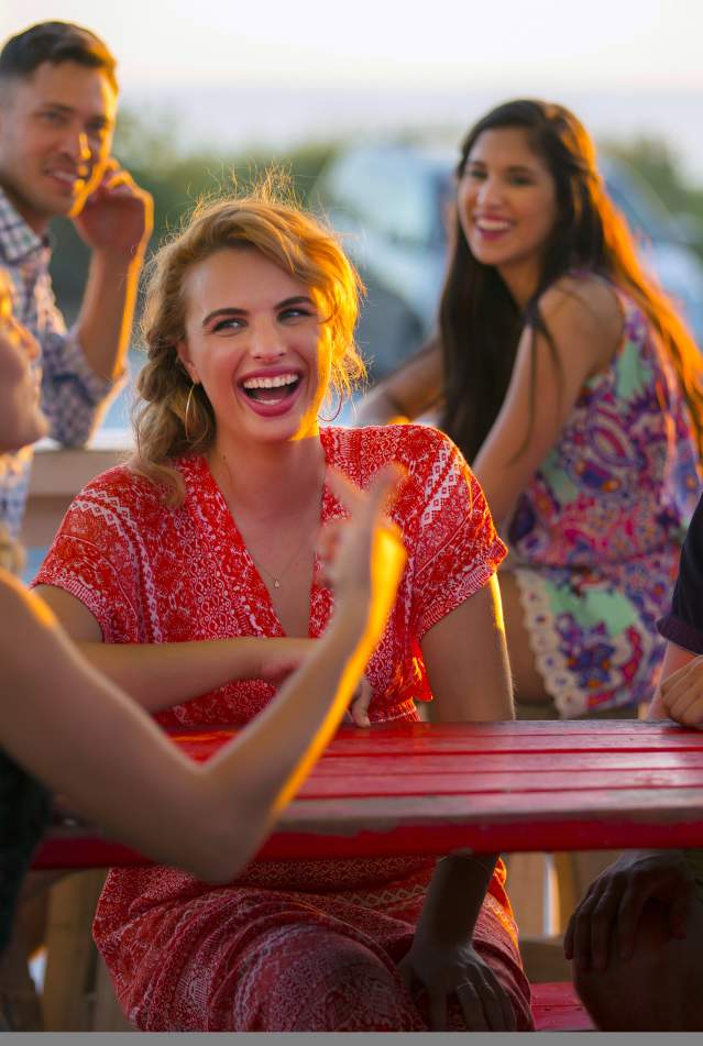 Millennials laughing and dining at sunset
